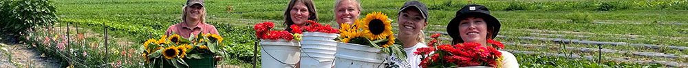 students pose with flowers grown at the organic farm