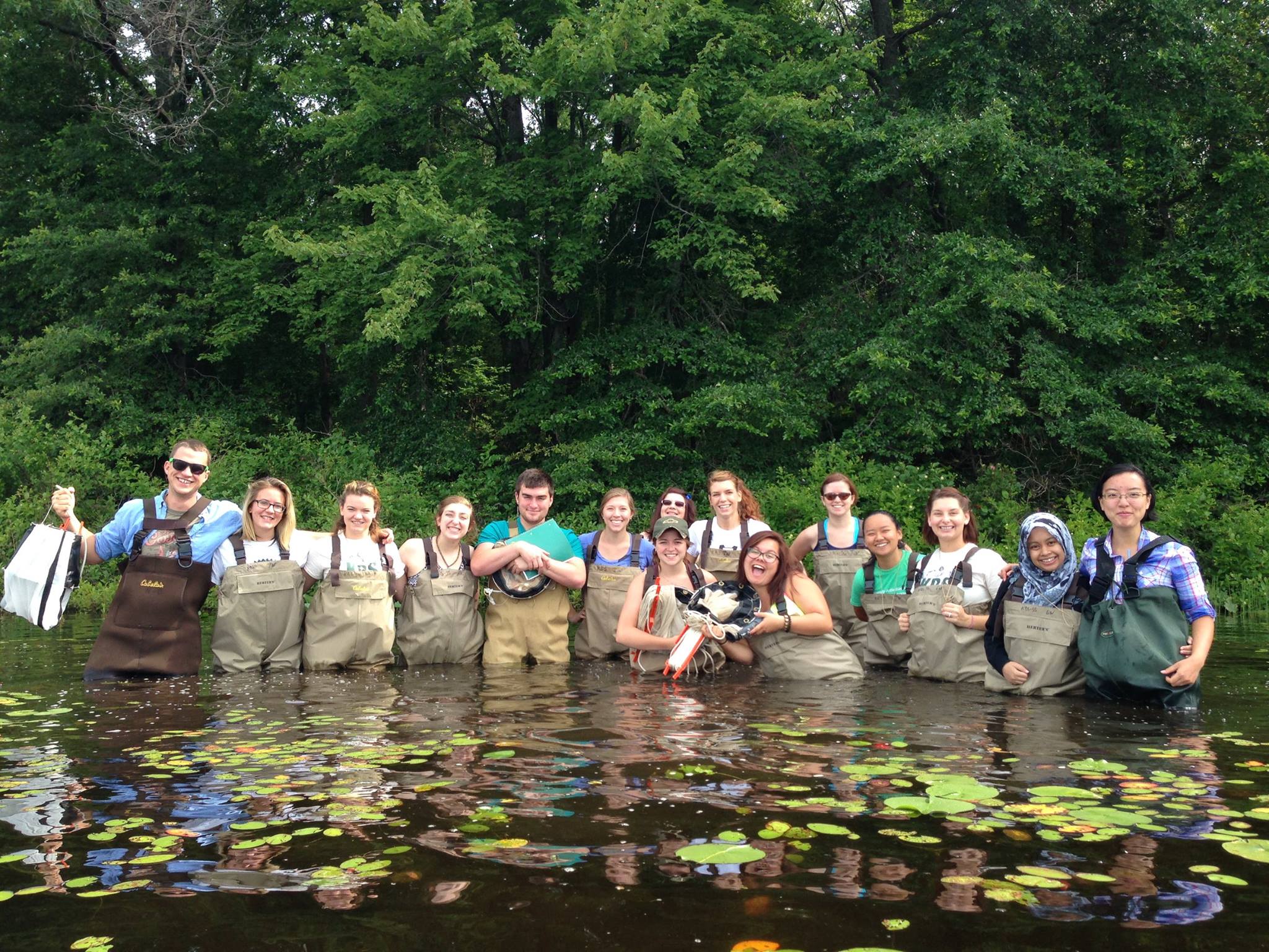 KBS summer course students standing in water with waders on, smiling at the camera.