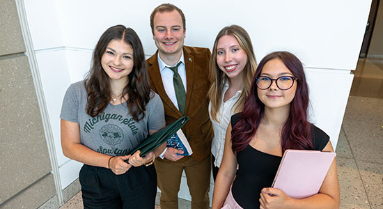 Three students stand together in business casual clothes on their way to their internship.