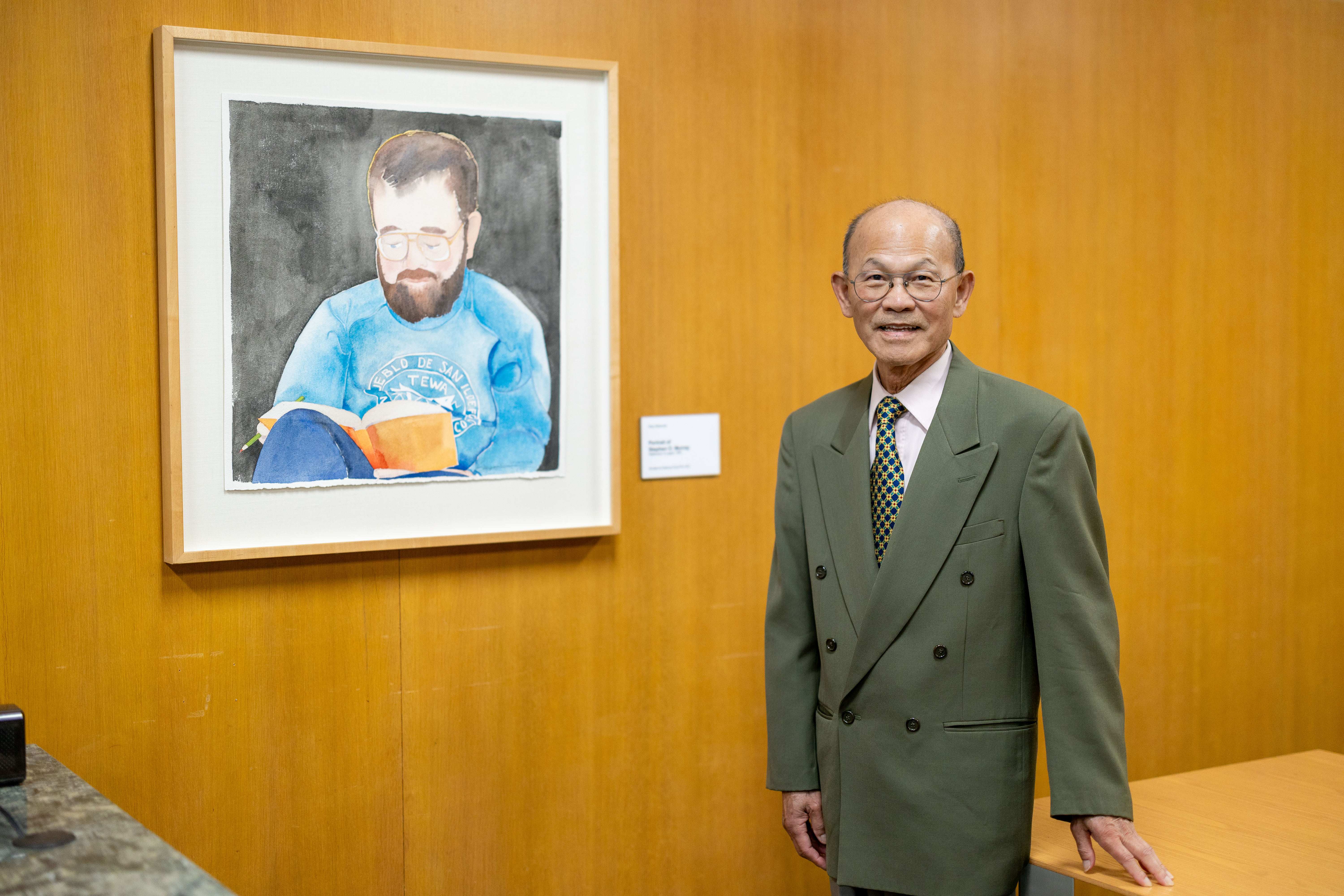 Keelung Hong stands next to a watercolor portrait of Stephen O. Murray.