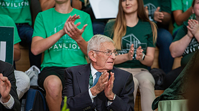Eli Broad clapping sitting in front of group of clapping students
