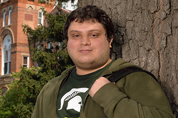 MSU student wearing leaning against tree